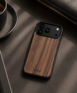 buko walnut wood case on a dark table next to a coffee in a black cup, a black leather bag and black pens.