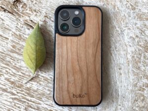 Buko natural wood iPhone case with slim black bumper on rustic timber surface with leaf