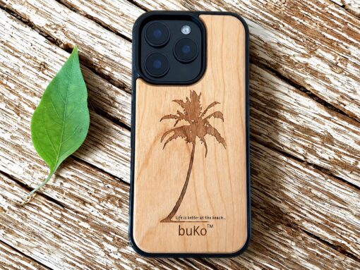 buko wooden phone case with palm tree on a rustic table next to a green leaf