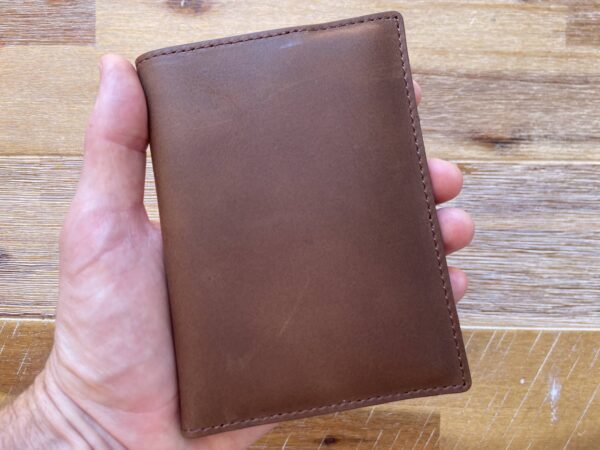 a hand holding a leather passport wallet