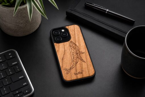 wooden phone case with a geometric whale engraving on a black minimalist desk