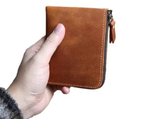 Holding light brown leather zip wallet