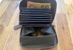 The stone kombi wallet open on a table with cards, cash and coins inside