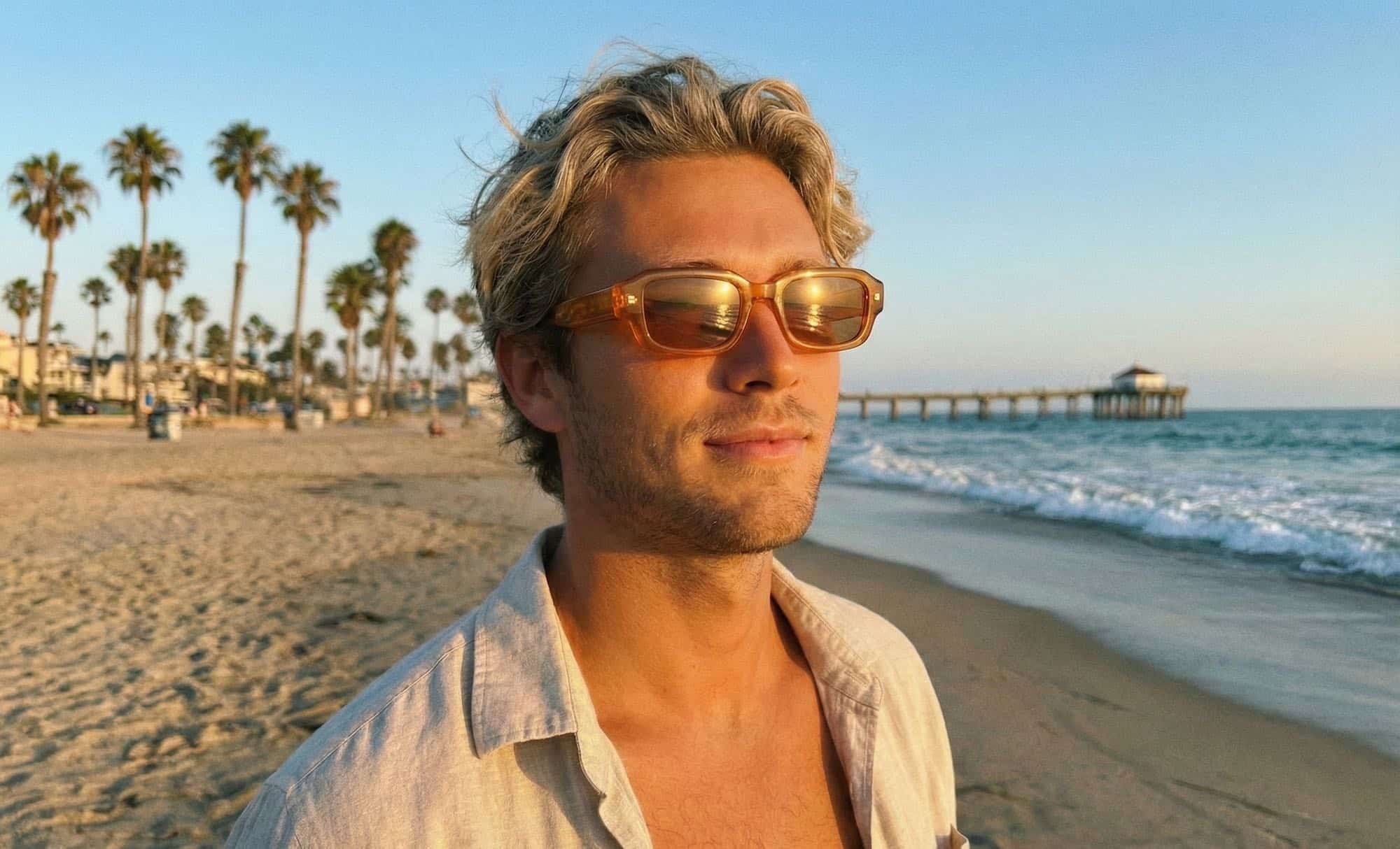 Man standing on a beach at sunset wearing Valley translucent amber sunglasses.