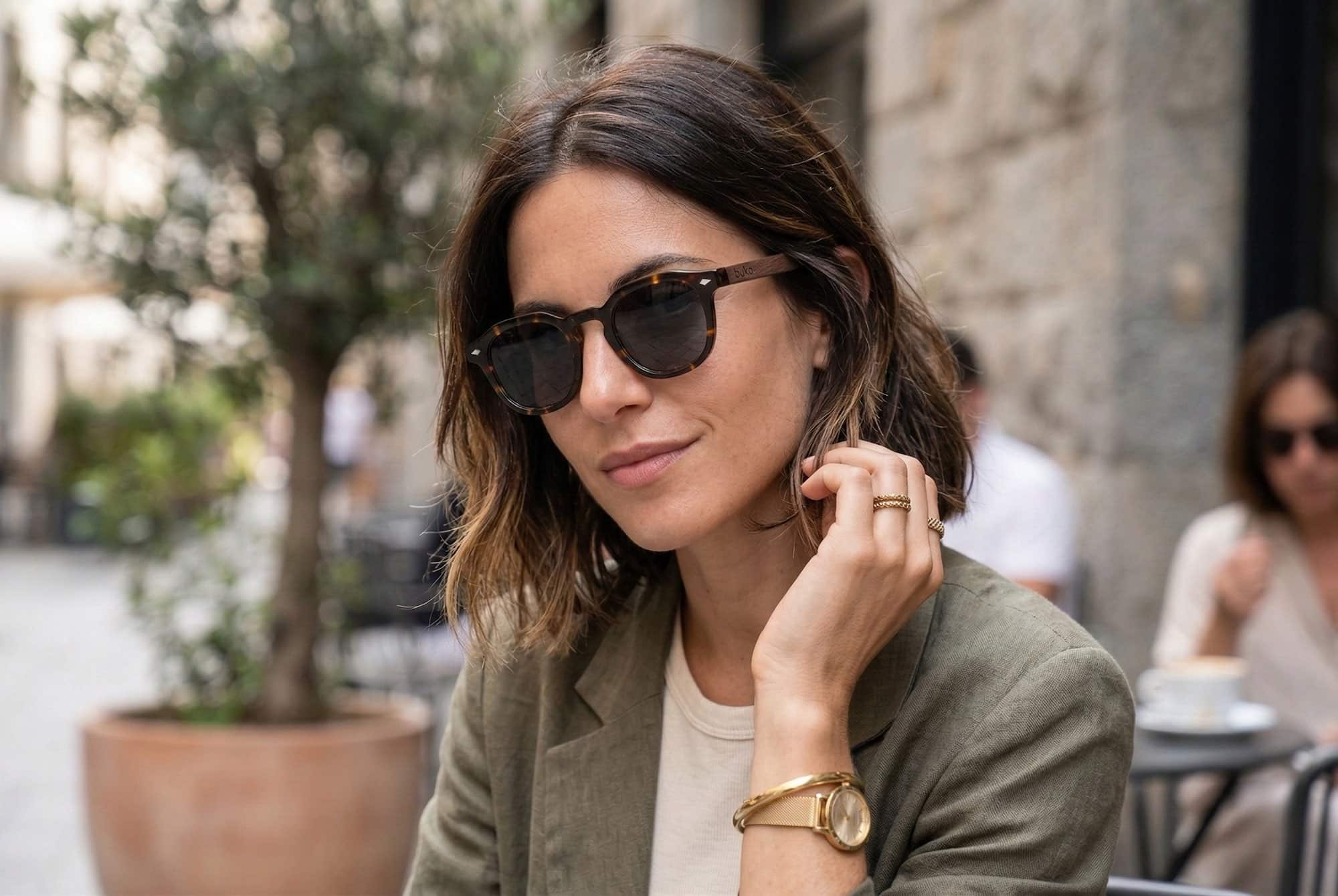 Capri tortoiseshell rounded sunglasses by Buko on female at outdoor cafe. 