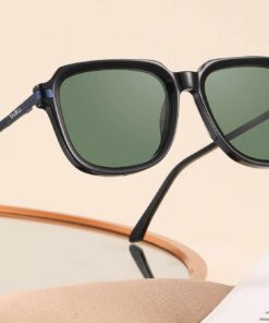 SoCal black acetate sunglasses with green polarised lenses displayed on a mirror and magazine.