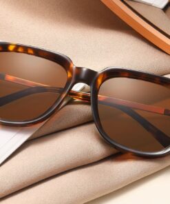SoCal tortoiseshell acetate sunglasses with brown polarised lenses displayed on fabric beside a magazine.
