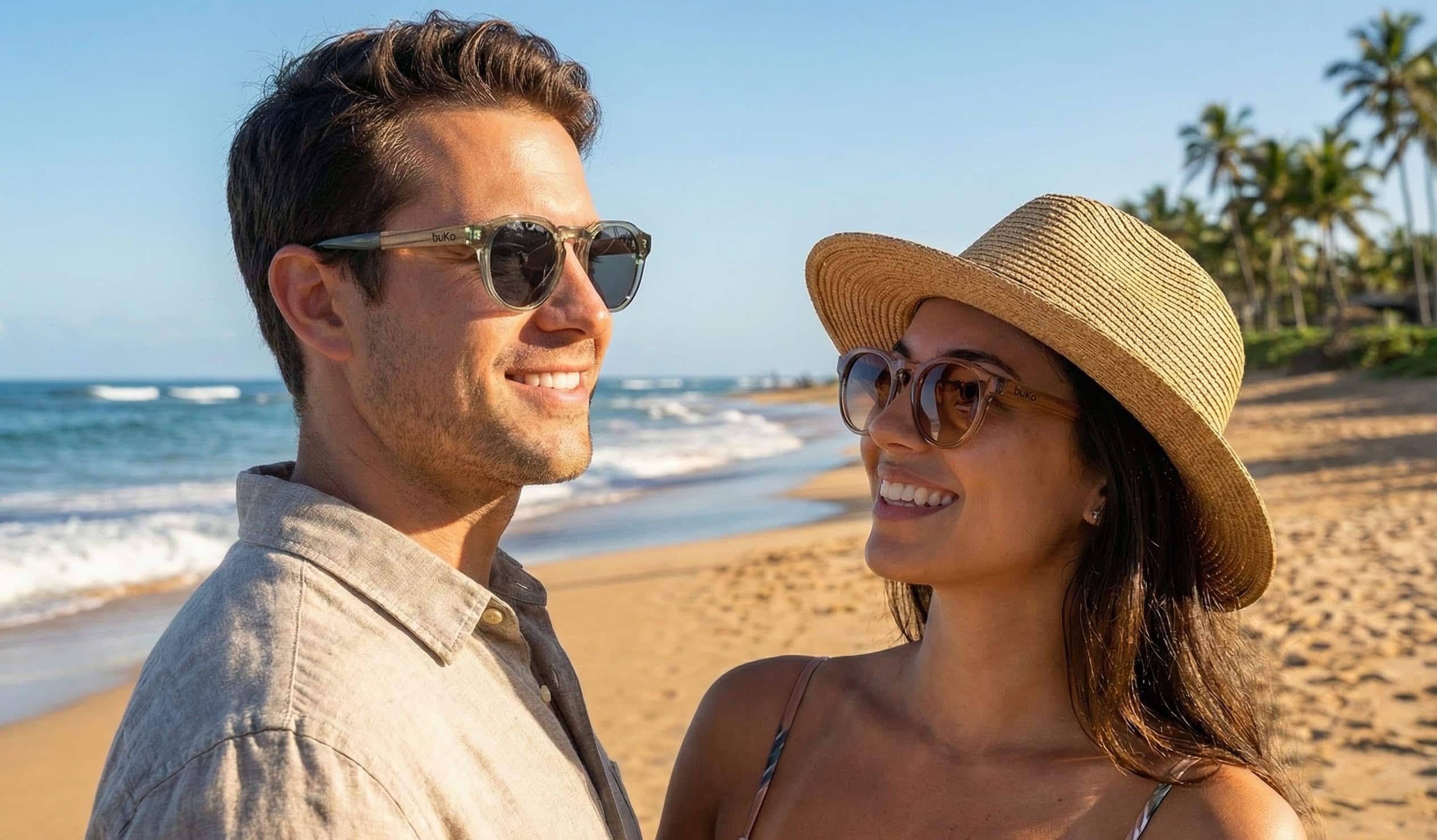 a male and female model wearing ocean sunglasses by buko on the beach