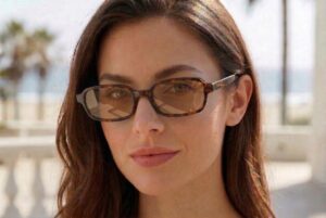 Female model wearing Cannes sunglasses by Buko with tortoiseshell frame and brown lenses at the beach in natural sunlight