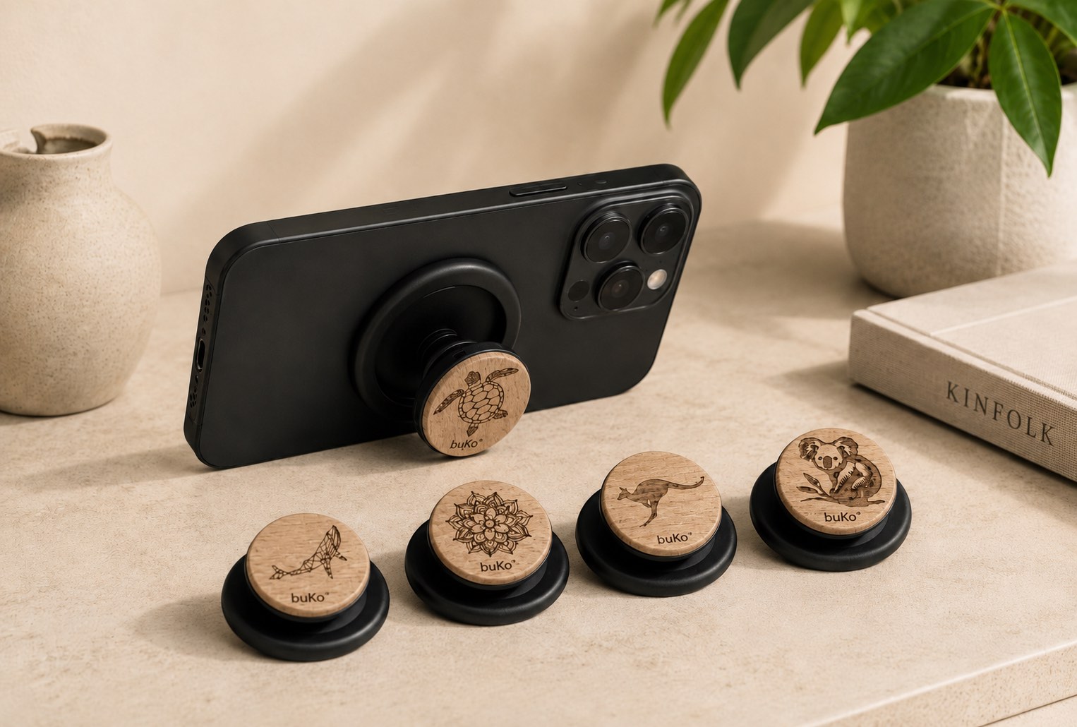 buKo MagSafe Phone Holder & Stand lifestyle image with black iPhone, turtle design holder, and engraved whale, mandala, kangaroo and koala styles