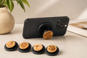 buKo MagSafe Phone Holder & Stand supporting a black iPhone with wooden turtle design and matching engraved styles displayed in front