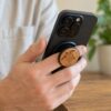 Person holding a black iPhone using the buKo MagSafe Phone Holder & Stand with engraved wooden turtle design