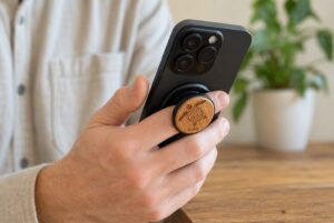 Person holding a black iPhone using the buKo MagSafe Phone Holder & Stand with engraved wooden turtle design