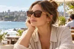 Woman wearing tortoiseshell Avoca sunglasses with wood temples at a coastal cafe